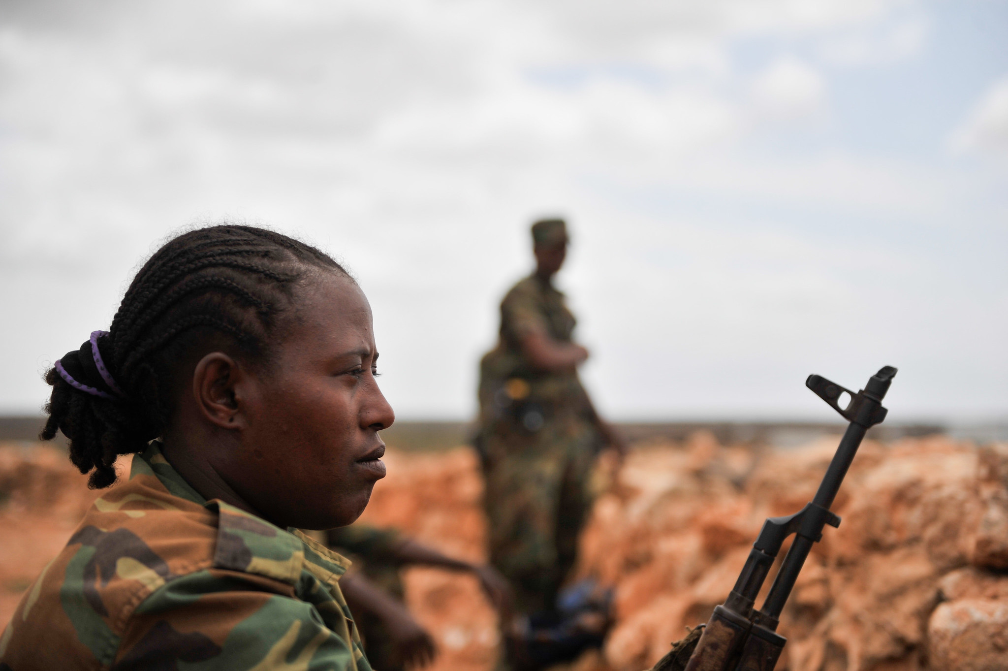 An Ethiopian soldier, wearing a military uniform and carrying a rifle, stands guard in Halgan village, Hiran region, Somalia, on June 10, 2016. The scene follows a recent battle against Al-Shabaab militants, during which AMISOM forces reportedly killed over 140 insurgents. The soldier’s posture and focused gaze reflect the tense atmosphere and the ongoing security operations in the area.