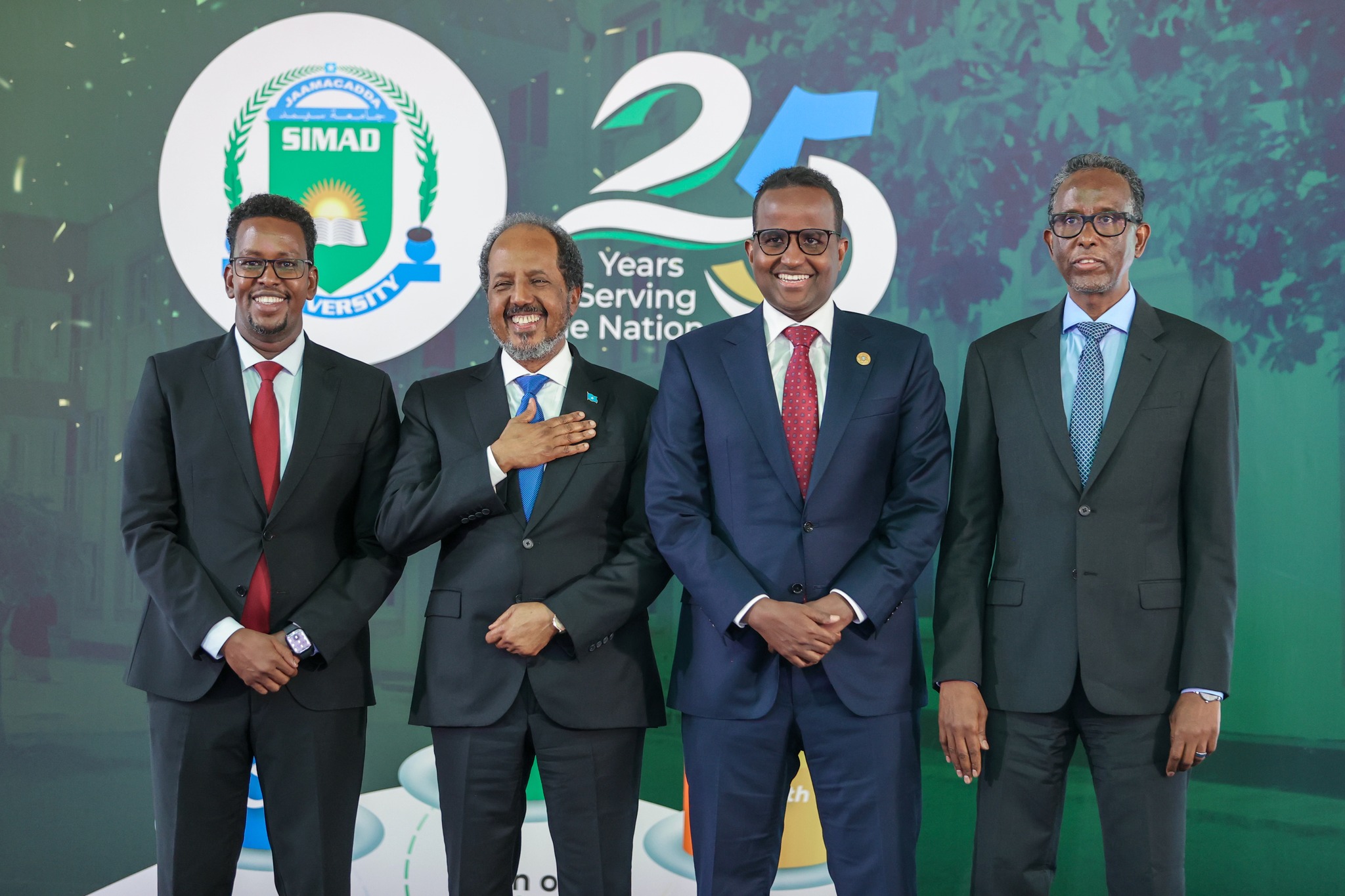 The current President of SIMAD University stands with three former Presidents of Somalia, all dressed in formal attire, during the university’s 25th-anniversary celebration.