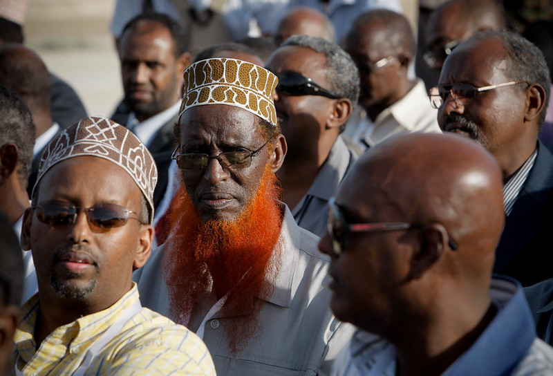 Newly elected parliamentarians seated in rows at Mogadishu Airport during the inauguration ceremony for Somalia's first parliament in twenty years, August 20, 2012. The image captures a historic moment in Somalia's governance, with participants in formal attire, symbolizing the restoration of parliamentary democracy.