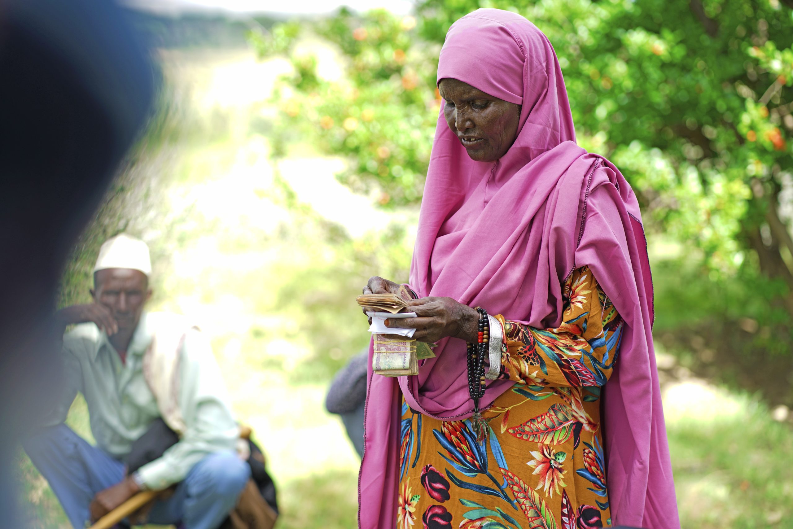 A woman in Booca village, Sanaag, Somaliland, participates in a Village Savings and Loan Association meeting, receiving her weekly savings and a disbursed loan on 10 May 2023.