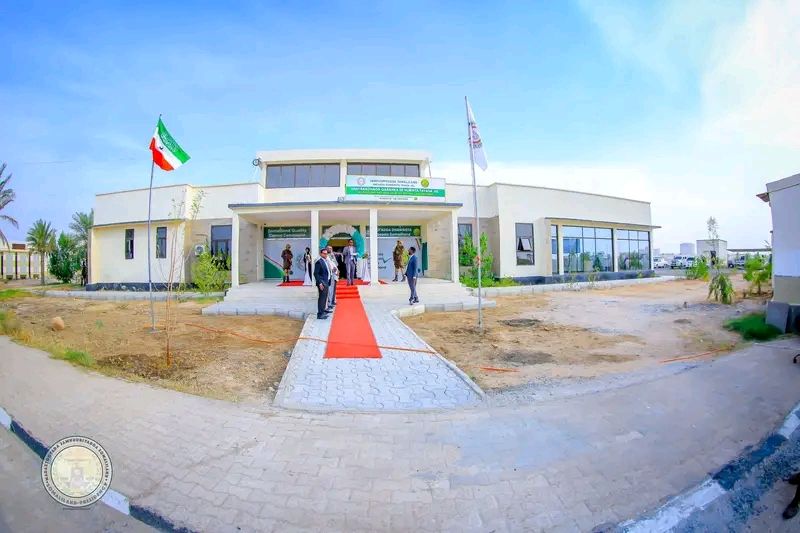 The National Quality Testing Laboratory of Somaliland (JSL), a newly inaugurated facility with a modern design. A red carpet leads to the entrance, with the Somaliland flag hoisted outside and officials present at the opening.