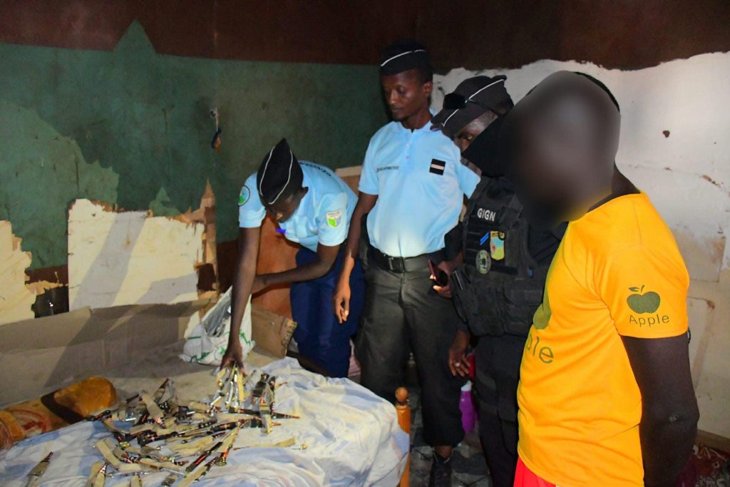 This is a picture showing the police forces inspecting people who were carrying illegal weapons. There are many knives scattered on the table