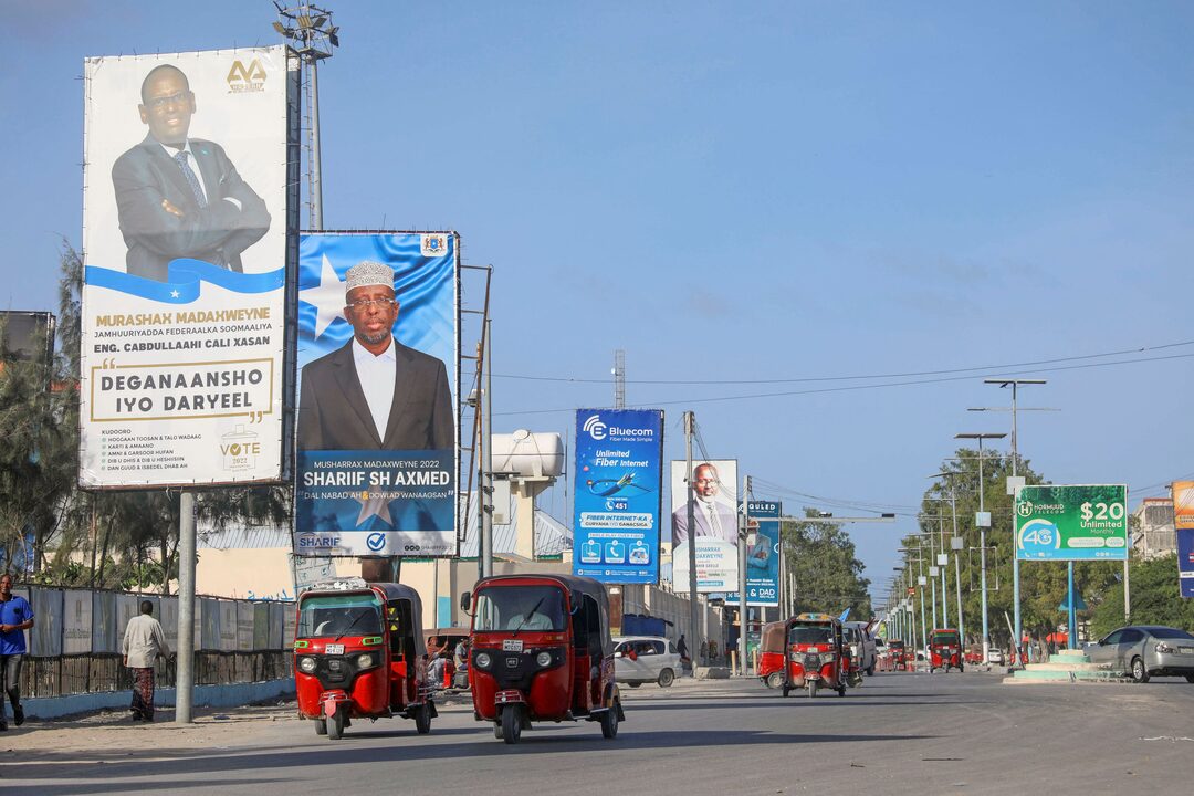 Busy street scene in Somalia with multiple billboards displaying political campaign ads for presidential candidates.