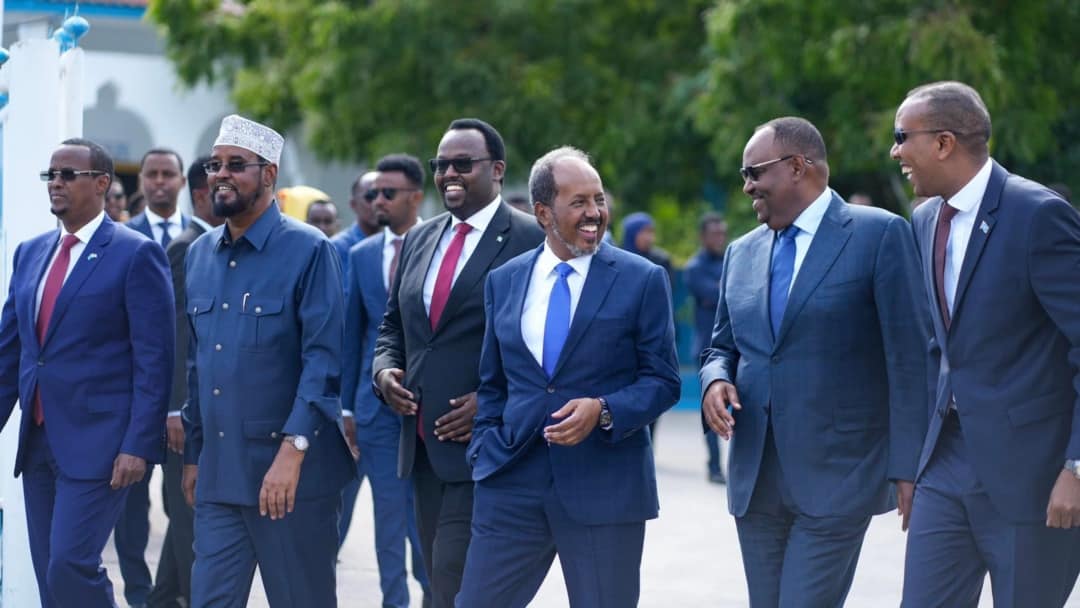 President Hassan Sheikh Mohamud walking alongside Federal Member State leaders and the Prime Minister of Somalia, all smiling outdoors near the Villa Somalia conference venue.