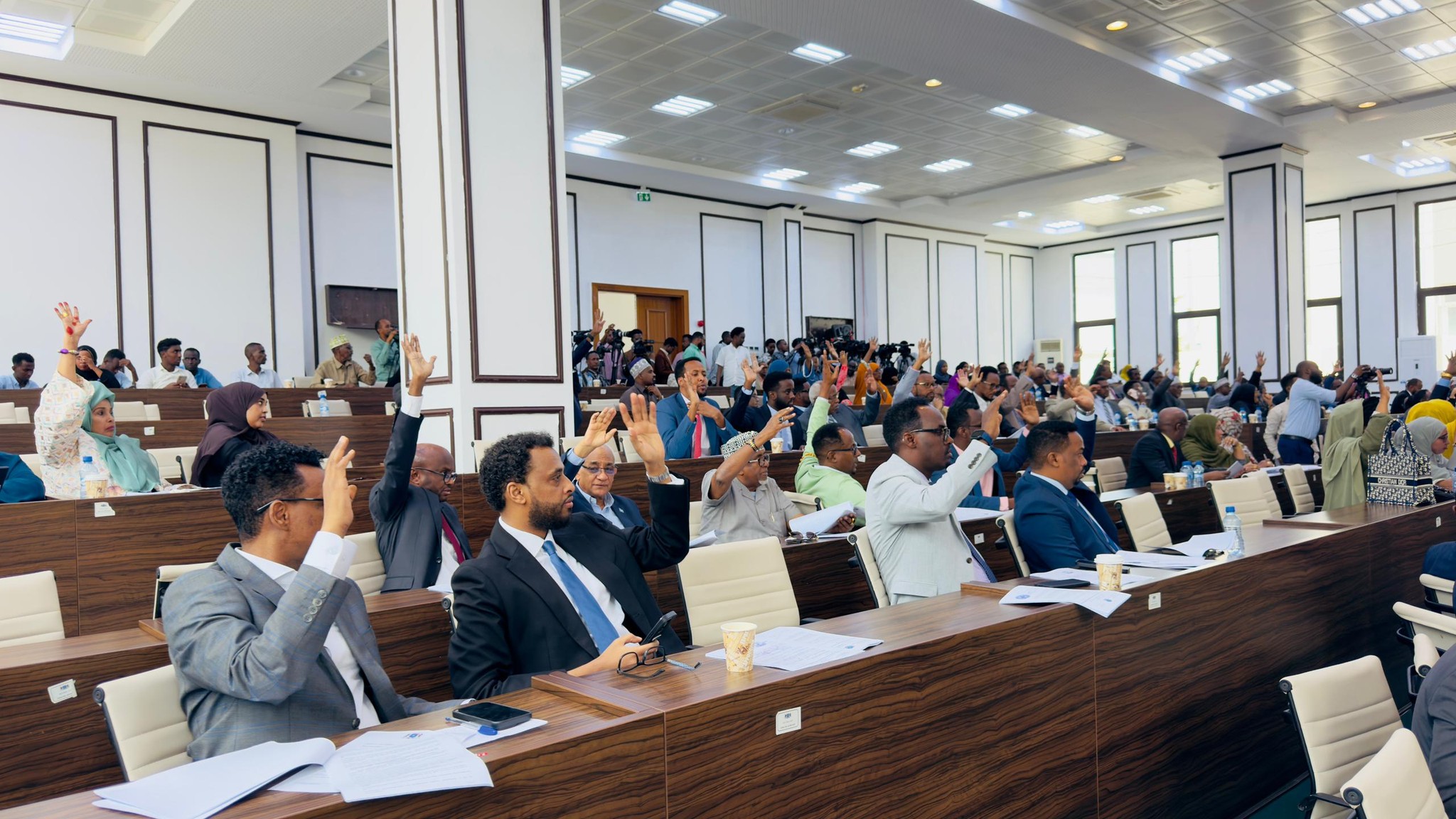 Members of Somalia’s House of the People seated during a parliamentary session, actively participating in a debate about salary deductions for military support.