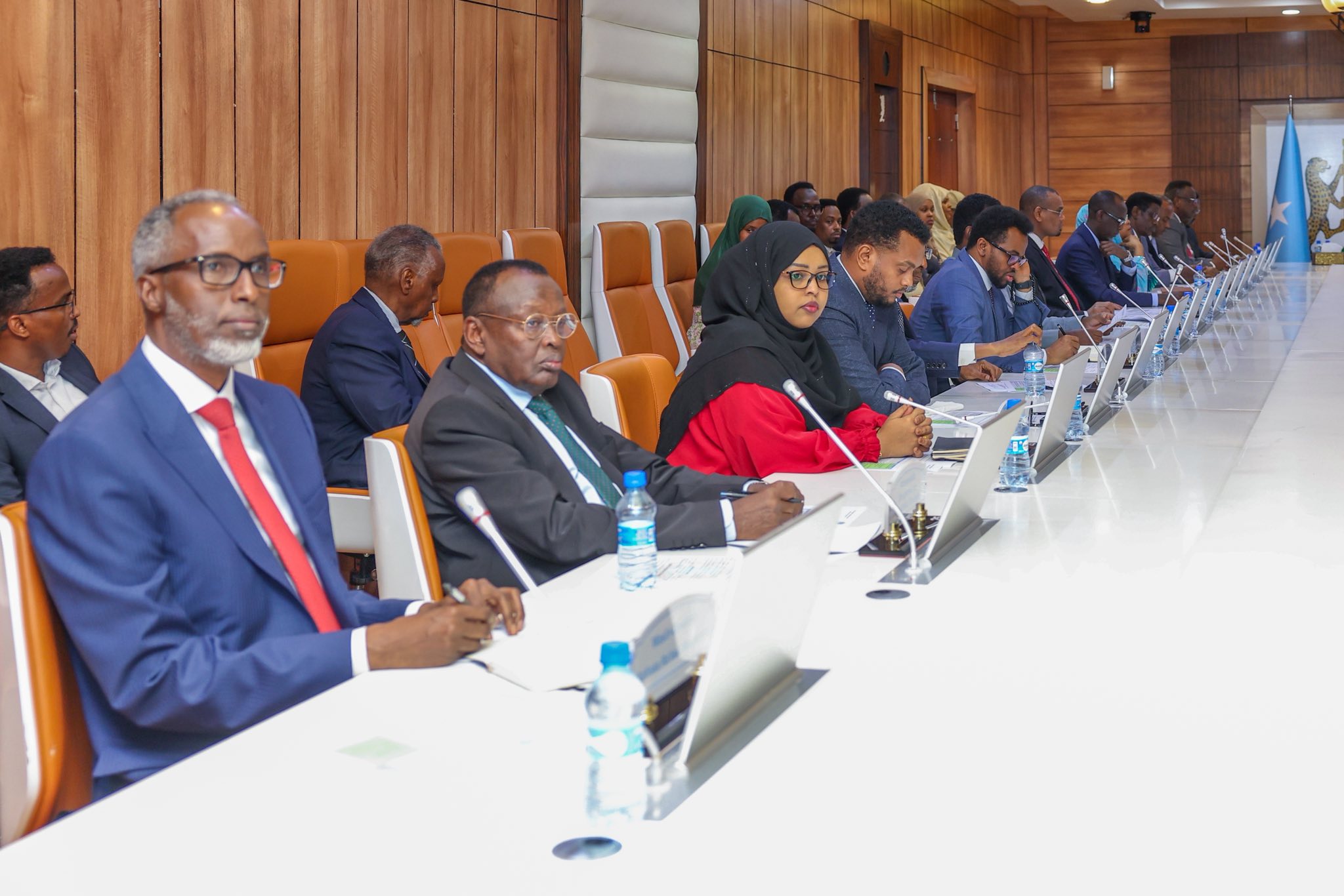 Somalia’s Cabinet members seated attentively during a weekly meeting in a modern conference room with microphones and laptops.